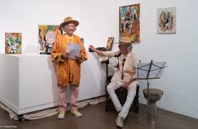 Stephen John Kalinich reading at his art opening with John Densmore seated beside him