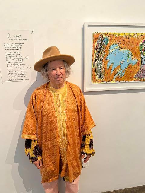 Stephen John Kalinich at his Los Angeles art opening, standing beside one of his framed paintings